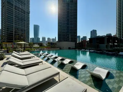 a swimming pool with lounge chairs and a city skyline at Skyline Escape 2 bedroom with Burj Khalifa View in Dubai