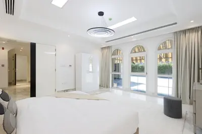 a white bedroom with a large bed and large windows at Exclusive Golf Villa 5BR with Pool and Game Room in Dubai