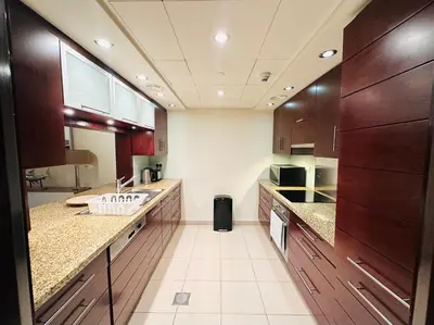 a large kitchen with wooden cabinets and a sink at Luxury 1BR Apartment at Burj Views Tower C - Downtown in Dubai