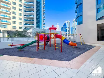 a playground with a slide in a courtyard at 1BR City Escape at Marina Residence Pool & Gym in Dubai