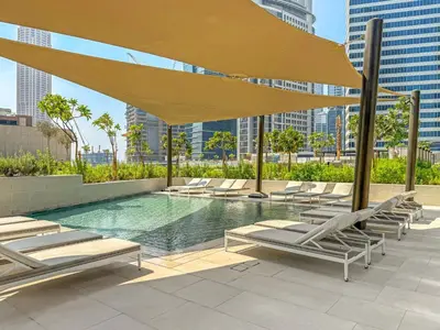 a pool with lounge chairs and a large yellow umbrella at VayK - Bright Studio Overlooking The Canal in Business Bay in Dubai