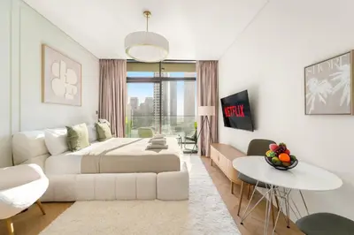 a white bedroom with a bed and a living room at VayK - Bright Studio Overlooking The Canal in Business Bay in Dubai