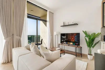 a living room with a white couch and a tv at Relaxing Studio with Balcony & Pool in Haven Tower in Dubai