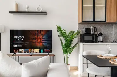 a living room with a tv and a table at Relaxing Studio with Balcony & Pool in Haven Tower in Dubai