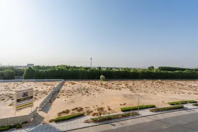 a large empty parking lot with trees and bushes at Relaxing Studio with Balcony & Pool in Haven Tower in Dubai