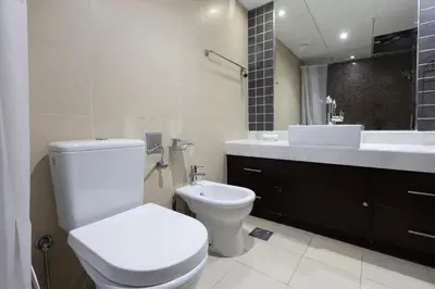 a bathroom with a toilet and a sink and a mirror at Stylish 2BR Oasis in Business Bay with Pool & Gym in Dubai