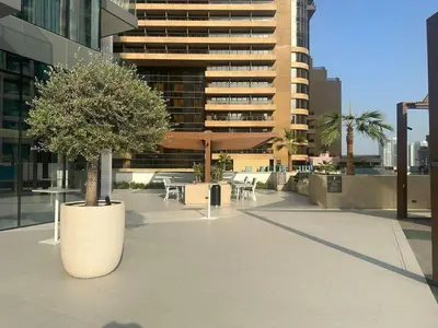 a courtyard with a tree and tables and a building at Luxury 1Bed at LIV Marina Stunning Marina Views in Dubai
