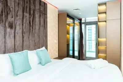 a bedroom with a large white bed with blue pillows at 2BR With Rooftop Pool Offering Burj Khalifa Views in Dubai