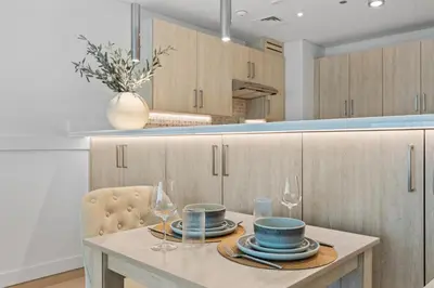 a kitchen with a table with plates and wine glasses at Palm Jumeirah Sea-View Stay - Infinity Pool - Beach - Gym - Padel in Dubai