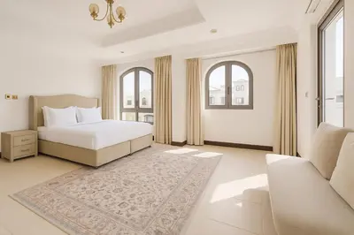 a bedroom with a bed and a couch and windows at BLVD Beach House in Dubai