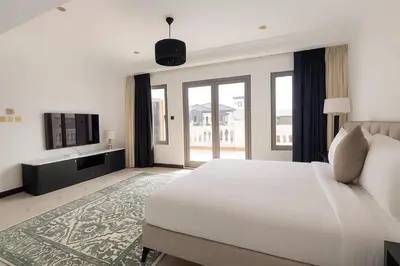 a white bedroom with a large bed and a television at BLVD Beach House in Dubai