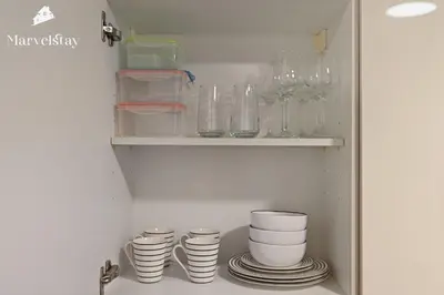 a cabinet with plates and glasses on a shelf at MarvelStay - Beach 5 mins - Fits 3 - Pool-Gym-Sauna - Marina in Dubai