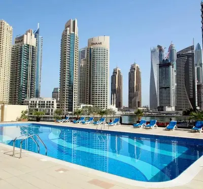 a swimming pool with chairs and a city skyline at Two Bedroom with Full marina view in Dubai