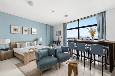 a bedroom with a bed and a table and chairs at Beachfront Boho Bliss Direct Beach Access in Dubai