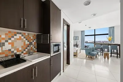 a kitchen with a sink and a living room at Beachfront Boho Bliss Direct Beach Access in Dubai
