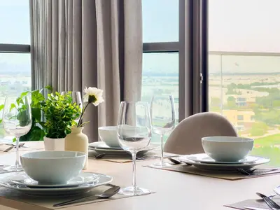 a table with plates and wine glasses on it at Greenery Haven 2 Bed plus Study in Damac Hills in Dubai