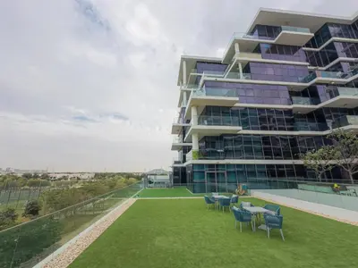 a building with chairs and a lawn in front of it at Greenery Haven 2 Bed plus Study in Damac Hills in Dubai