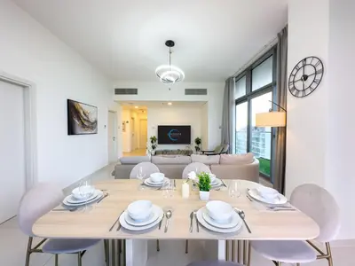 a dining room with a table and chairs and a couch at Greenery Haven 2 Bed plus Study in Damac Hills in Dubai