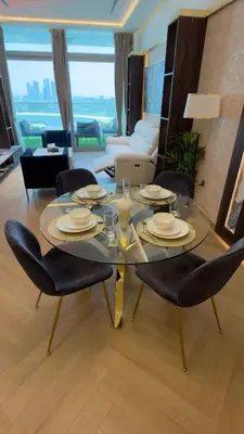 a glass table and chairs in a living room at Beachside Palm Jumeirah 1 Br apartment in Dubai