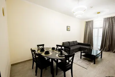 a living room with a table and chairs and a couch at Brand New 2BHK Fully Furnished Apartment in Warsan in Dubai