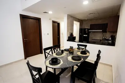 a dining room with a table and chairs and a kitchen at Newly Furnished 1BHK Apartment in Maya Residency in Dubai