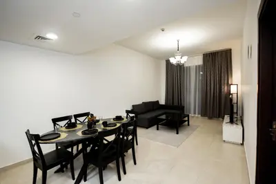 a dining room and living room with a table and chairs at Newly Furnished 1BHK Apartment in Maya Residency in Dubai