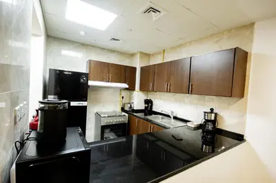 a kitchen with wooden cabinets and a black counter top at Newly Furnished 1BHK Apartment in Maya Residency in Dubai