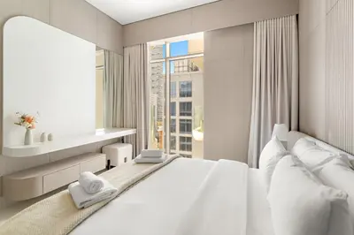 a white bedroom with a large bed and a window at VayK - Refined 1 BD Apartment in JVC in Dubai
