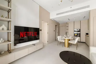 a living room with a television and a table with chairs at VayK - Refined 1 BD Apartment in JVC in Dubai