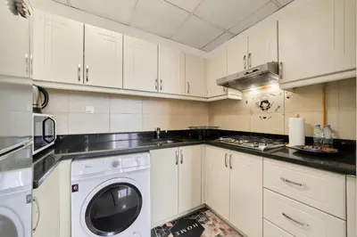 a kitchen with white cabinets and a washing machine at Peaceful 1BR with Balcony at Elite Residence Dubai in Dubai