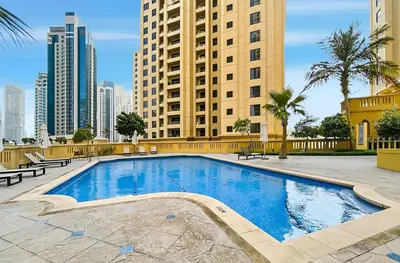 a large swimming pool in front of tall buildings at 2BR Marina View Steps from the Beach in Dubai