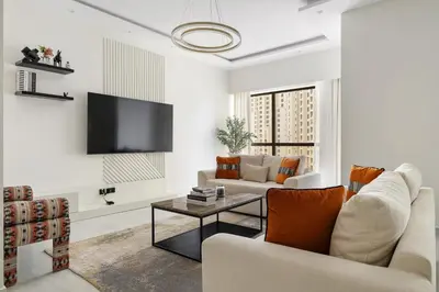 a living room with white furniture and a flat screen tv at 2BR Marina View Steps from the Beach in Dubai