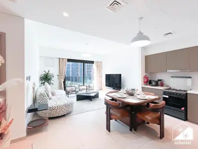 a kitchen and living room with a table and a couch at Skyline Escape 2BR Stay with balcony, Pool & Gym in Dubai