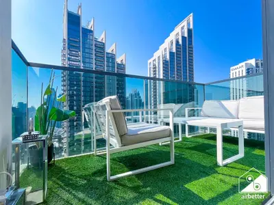 a balcony with a white chair and a view of a city at Skyline Escape 2BR Stay with balcony, Pool & Gym in Dubai