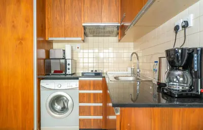 a kitchen with a washing machine and a sink at Zapbed House-Modern Studio Apartment in Dubai Sports City in Dubai
