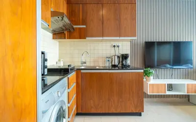 a kitchen with wooden cabinets and a washer and dryer at Zapbed House-Modern Studio Apartment in Dubai Sports City in Dubai