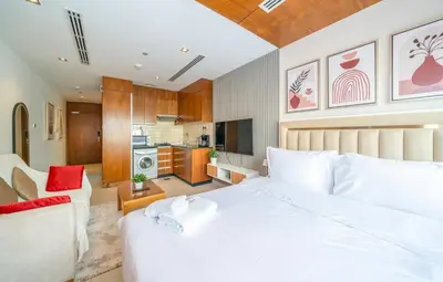 a bedroom with a white bed and a kitchen at Zapbed House-Modern Studio Apartment in Dubai Sports City in Dubai
