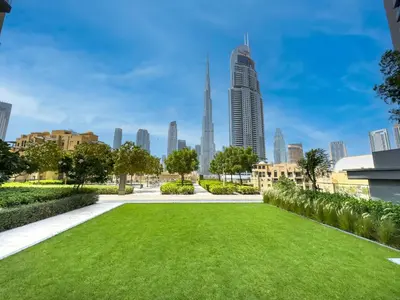 a park with a green lawn in front of a city at NEW 1BR in DOWNTOWN I 100m Walk to DUBAI MALL I Amazing POOL with Burj View in Dubai