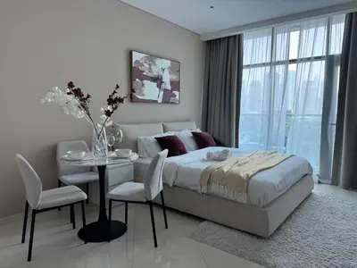 a white bedroom with a bed and a table and chairs at Comfortable apartments on the Palm in Dubai