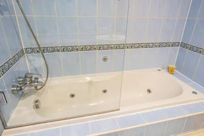 a white bath tub in a blue tiled bathroom at Elegant 1-BDR with Panoramic Marina & Canal Views in Dubai