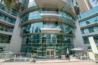 a large glass building with a revolving door at Elegant 1-BDR with Panoramic Marina & Canal Views in Dubai