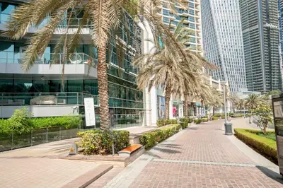 a street with palm trees in front of a building at Elegant 1-BDR with Panoramic Marina & Canal Views in Dubai