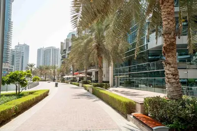 a sidewalk with palm trees next to a building at Elegant 1-BDR with Panoramic Marina & Canal Views in Dubai