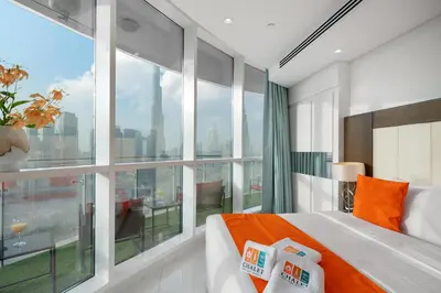 a bedroom with a large window and a bed with orange pillows at Full Burj Khalifa View New Year Fireworks - DAMAC Maison Distinction in Dubai