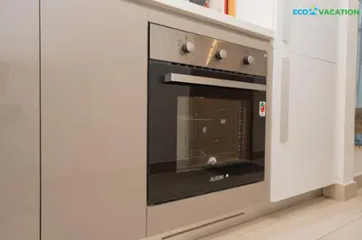 a black oven in a kitchen with white cabinets at Riviera Haven Boutique Stay with Wooden Charm in Dubai
