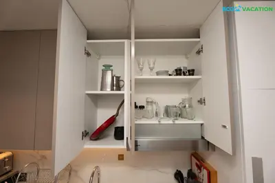 a kitchen with white cabinets and a sink at Riviera Haven Boutique Stay with Wooden Charm in Dubai