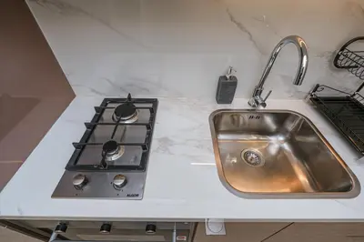 a kitchen counter with a sink and a stove at The Riviera Nook Cozy Stay in Dubai in Dubai