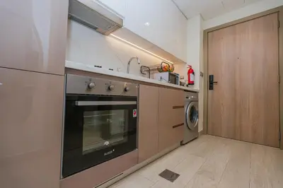 a kitchen with a stove and a washer and dryer at The Riviera Nook Cozy Stay in Dubai in Dubai