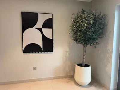 a plant in a white vase next to a painting at Coastal Chic at Emaar Beachfront 1BR in Dubai