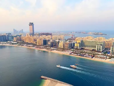 an aerial view of a city with a boat in the water at Coastal Chic at Emaar Beachfront 1BR in Dubai